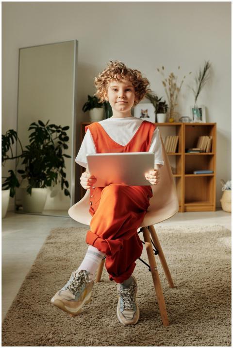 Smiling child with curly hair using a tablet in a