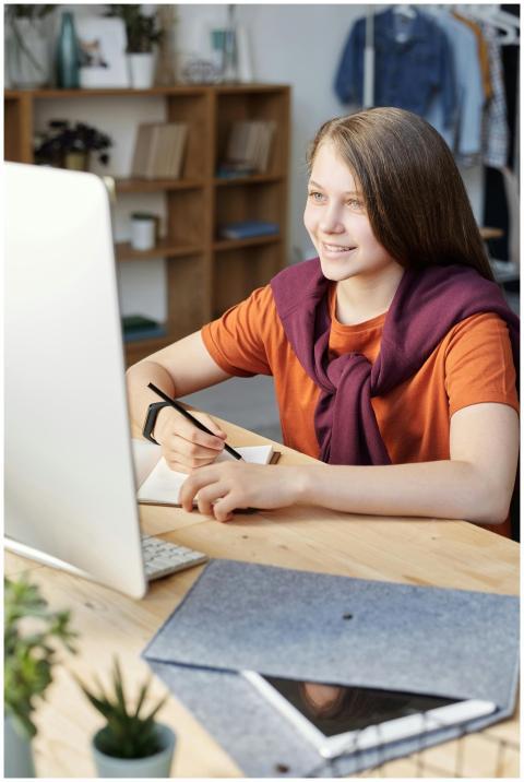 Smiling teen girl studying online at her home desk