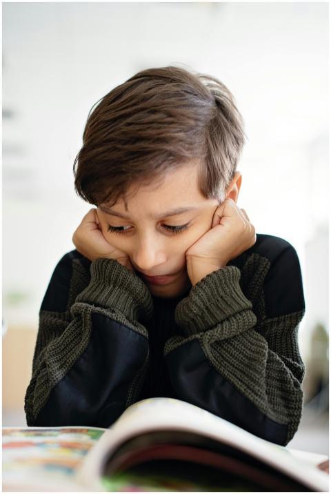 A young child in deep thought while reading a book