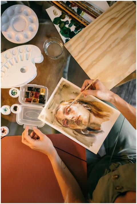 An artist paints a detailed watercolor portrait, s