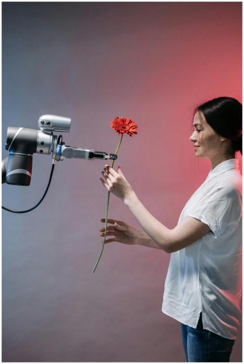 A woman interacts with a robotic arm holding a flo