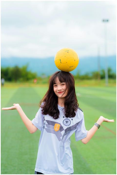 Young woman smiling while balancing a soccer ball