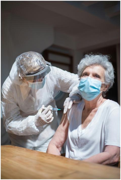 Elderly woman receiving a vaccine from a healthcar