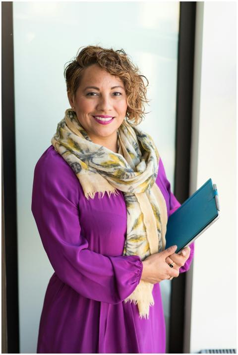 Smiling woman in a purple dress and scarf holding