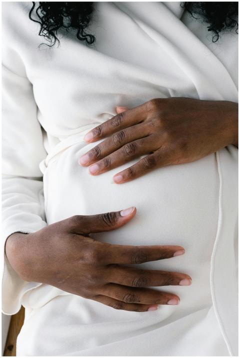 Close-up of a pregnant woman in white attire, gent