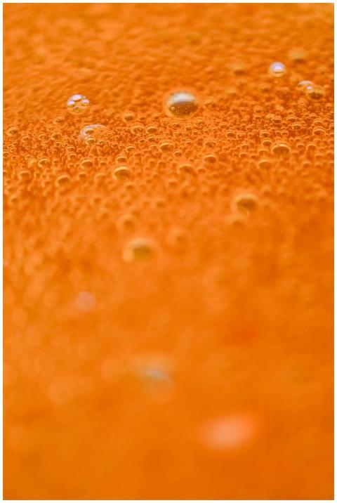 Detailed close-up of orange juice with bubbles, pe