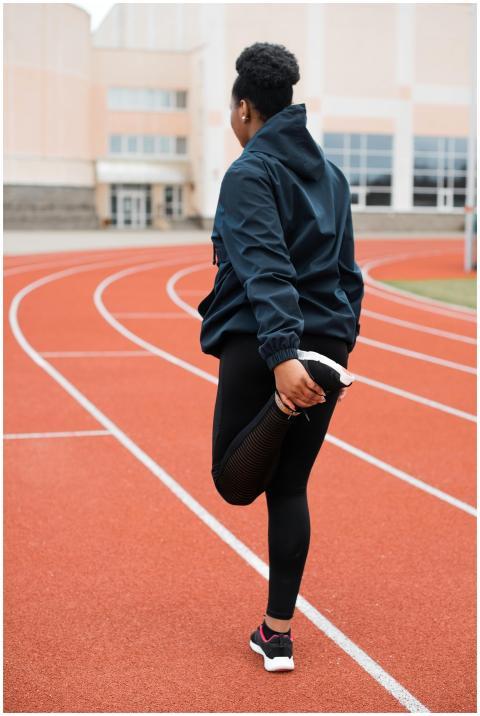 A woman is stretching on a track, showcasing fitne