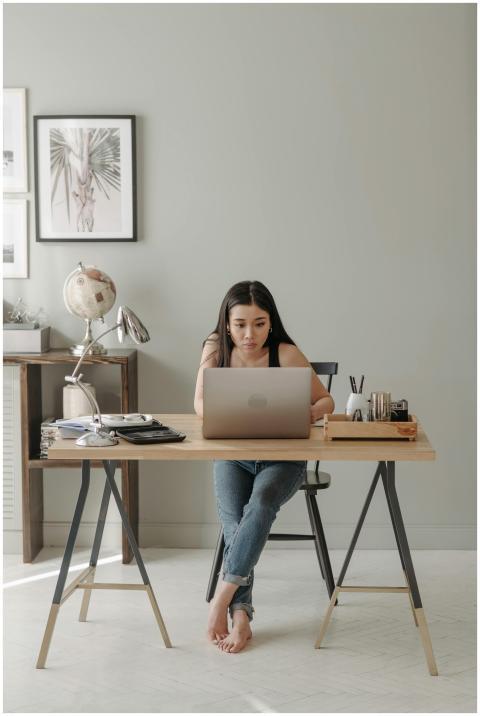 Asian woman focused on laptop work at a home offic