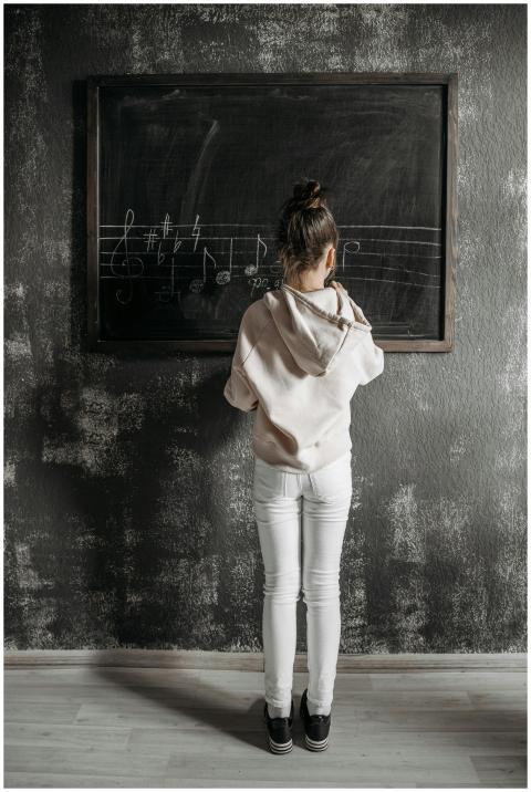 A child stands at a blackboard in a music studio w