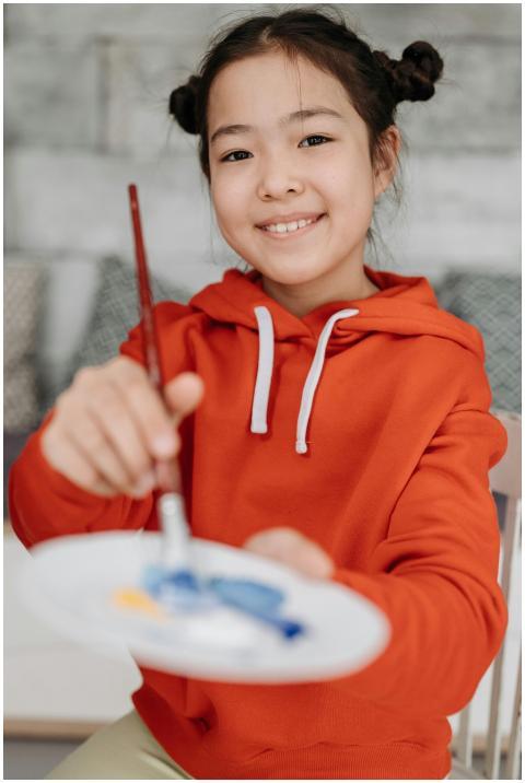 Smiling child in orange hoodie painting with water