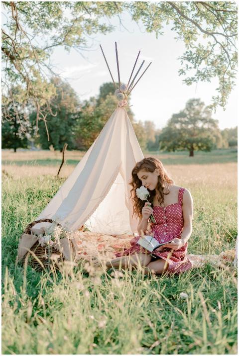 A woman in a polka dot dress enjoys a book and flo