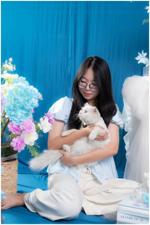 Woman gently holding a white cat in a floral-theme