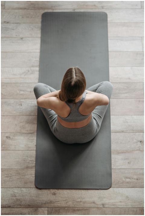 Top view of a woman in a gray outfit meditating on