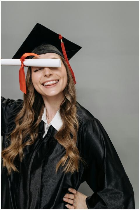 Smiling woman in graduation gown celebrating with