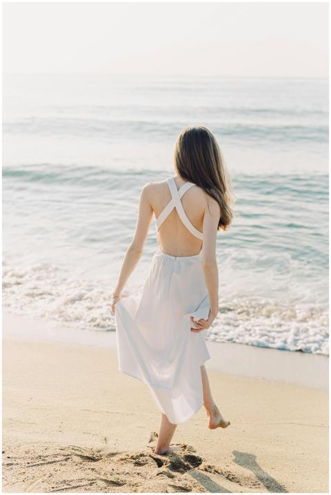 Rear view of a woman walking along a sunny beach,