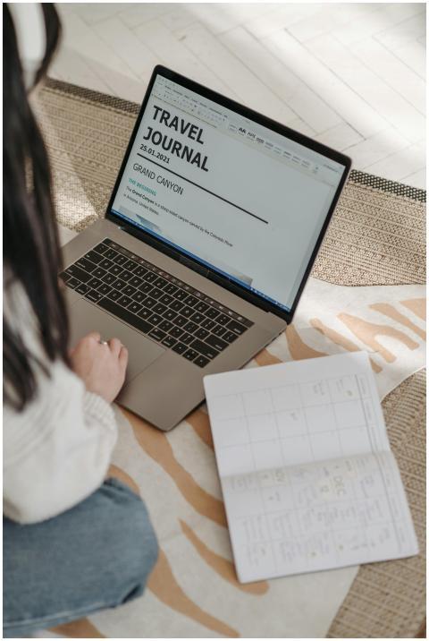 A young woman plans a travel journal using a lapto