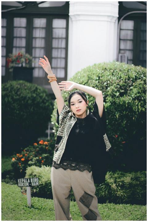 A young woman in stylish attire poses gracefully i