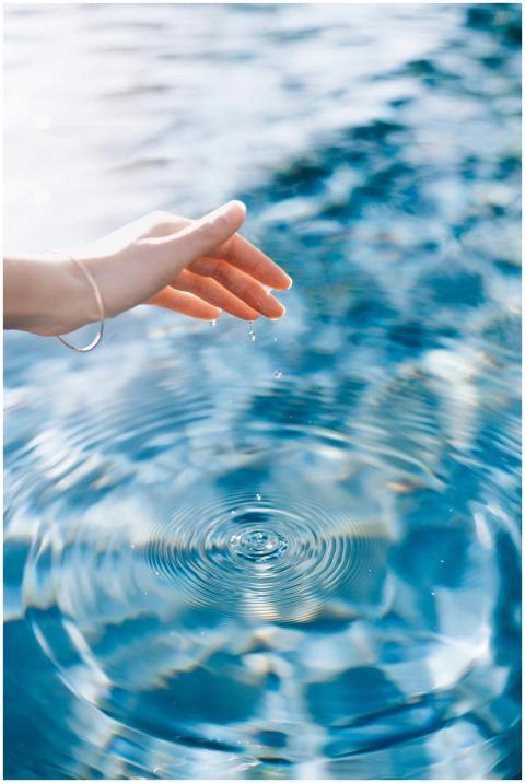 A woman's hand gently creates ripples on the surfa
