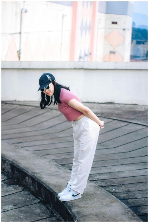 A stylish young woman in a cap and crop top poses