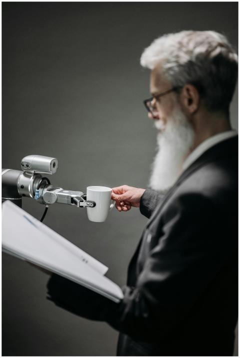 Elderly man interacts with robot arm holding a cup