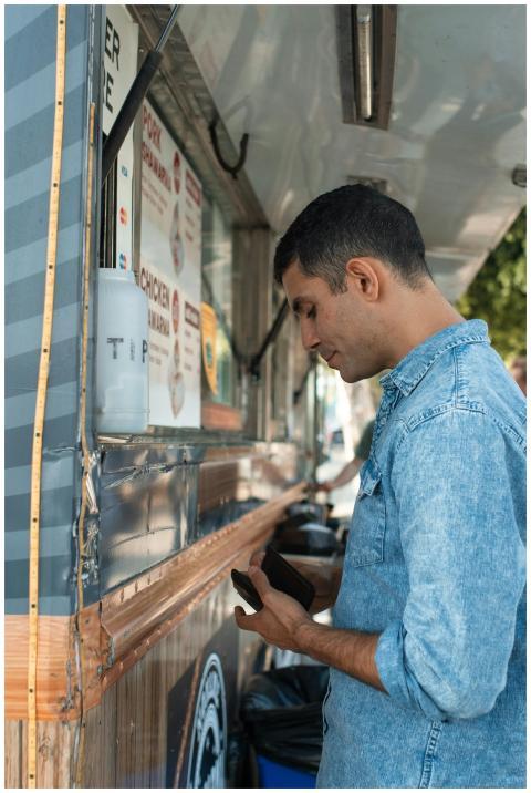Man in denim shirt ordering food from a street foo