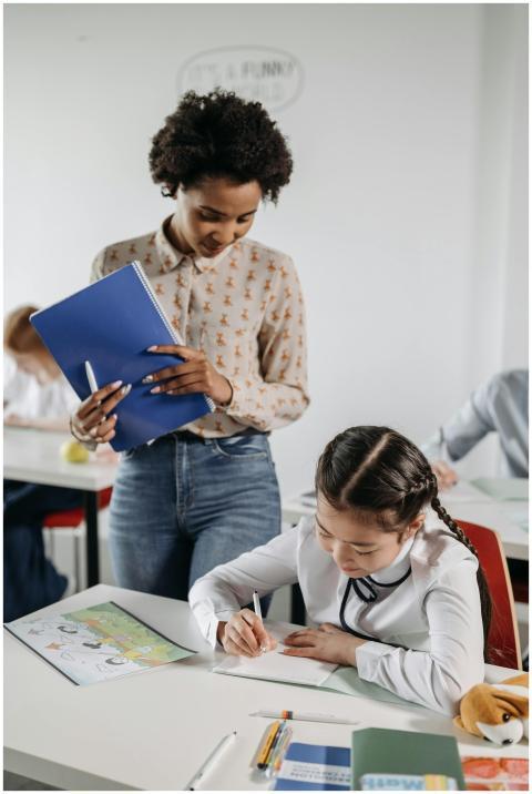 A diverse teacher helps a student with schoolwork