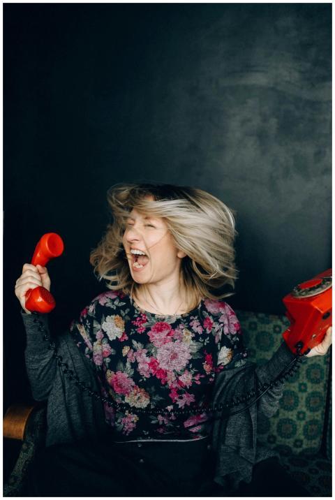 A woman angrily shouting into a vintage red teleph