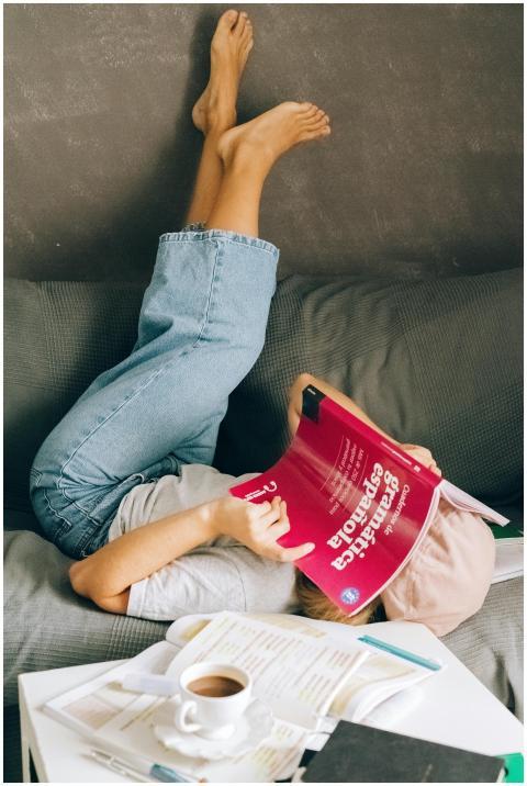 Young woman relaxes upside-down on a couch while s