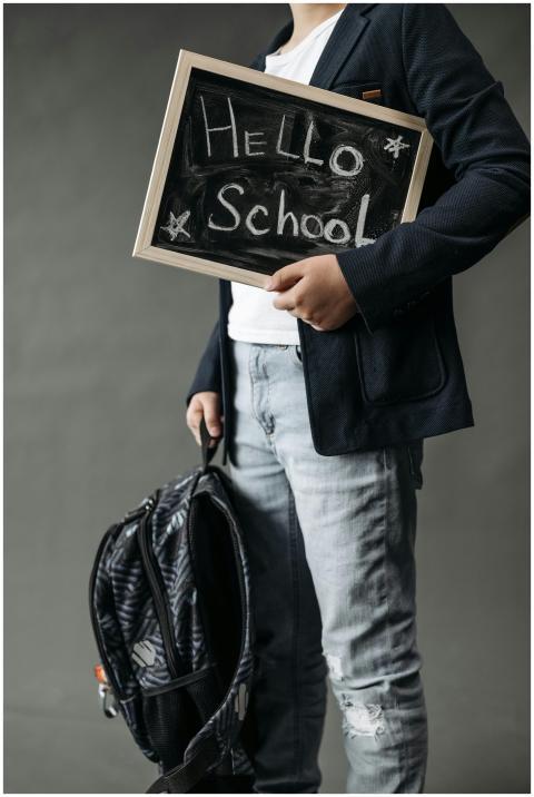 A student in casual attire holds a small chalkboar