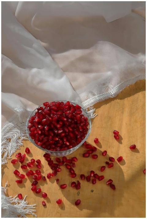 A glass bowl of vibrant pomegranate seeds on luxur