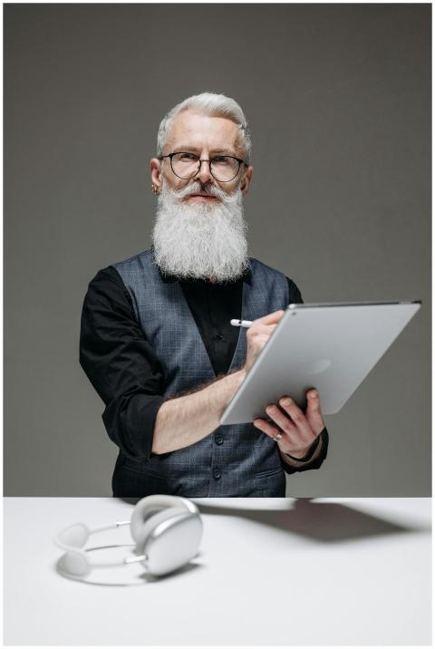 Elderly man with a white beard using a tablet and