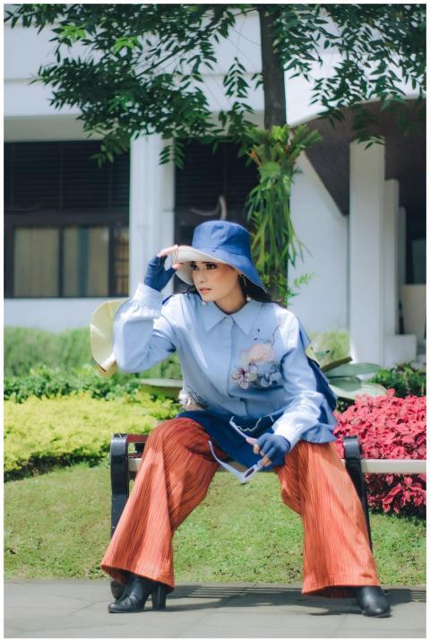 Stylish woman in vibrant outfit posing on a bench