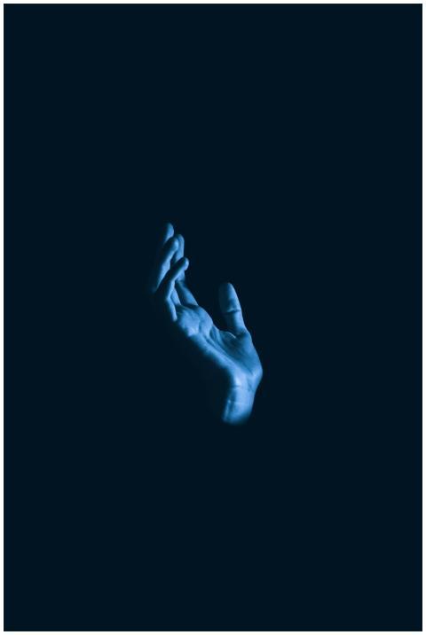 A single raised hand against a dark background, ev