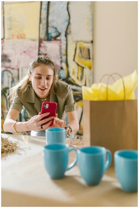 Woman using smartphone surrounded by cups and bag,