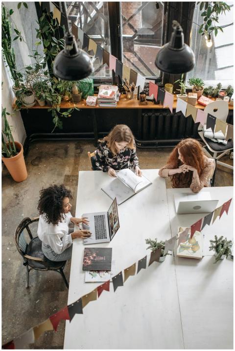 Three women collaborate creatively in a cozy indoo