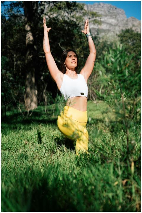 A woman in a yoga pose outdoors, amidst lush green