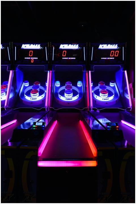 Vibrant and illuminated ski ball machines in a dar
