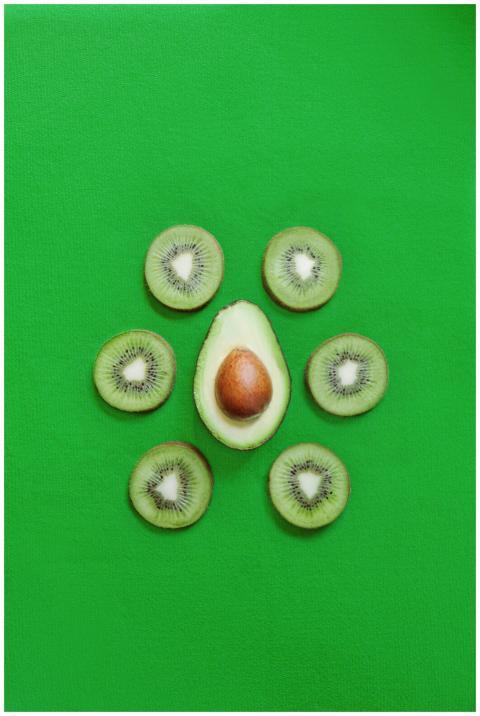 Top view of halved fresh avocado placed on green t