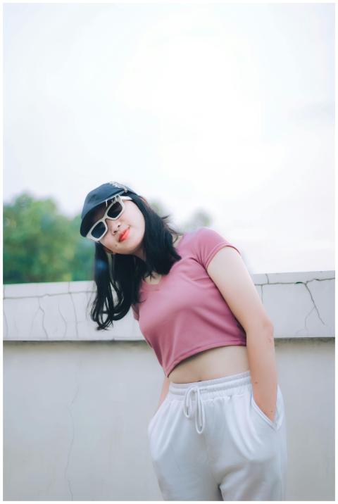 Young woman in casual attire with sunglasses poses
