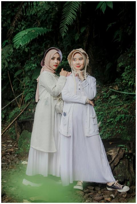 Two women in stylish hijabs and dresses pose elega