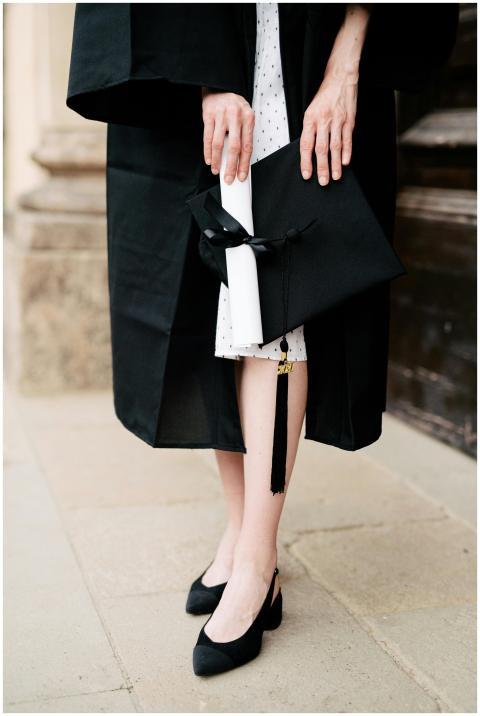 Close-up of a graduate holding diploma and cap in