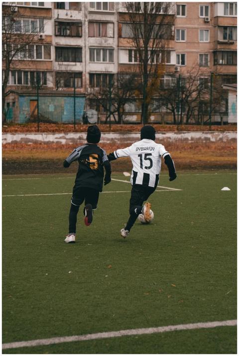 Two youths engaged in a soccer match on a grass fi