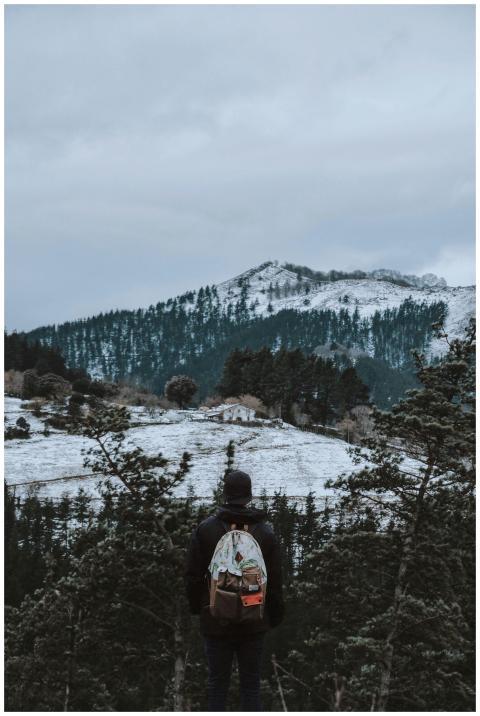 A lone hiker stands with a backpack, overlooking a
