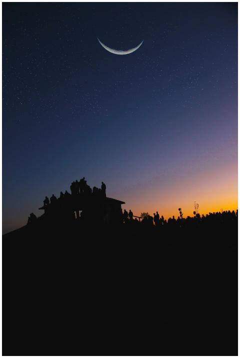 Silhouette of people under a crescent moon and sta