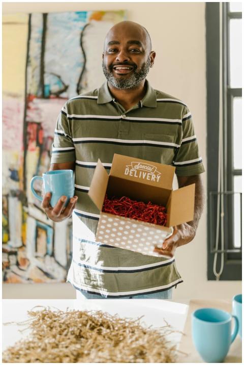 Entrepreneur holding a delivery box and mug, showc