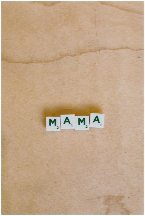 Four wooden Scrabble tiles spelling 'MAMA' on a na