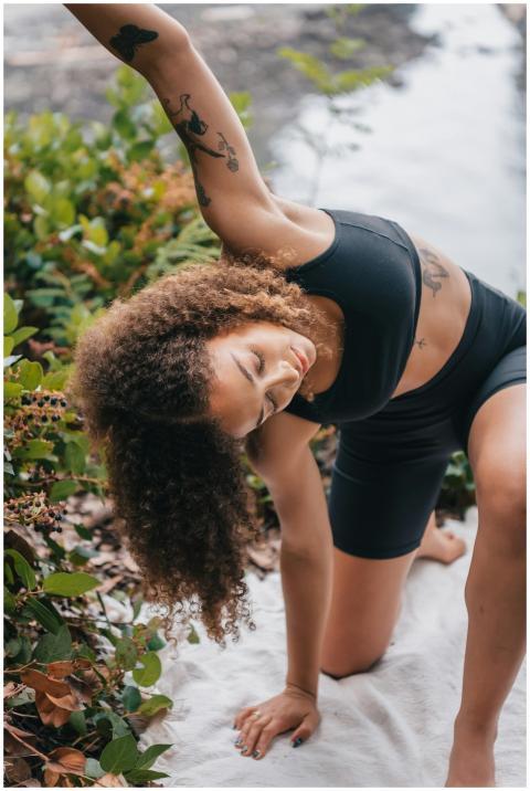 Woman stretching in activewear outdoors by a river