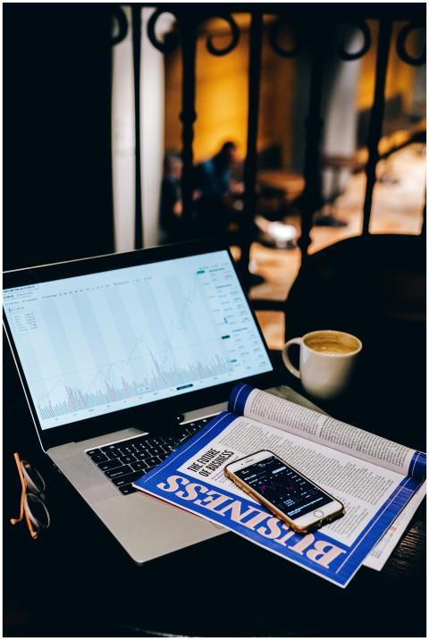 A laptop showing financial charts beside a busines