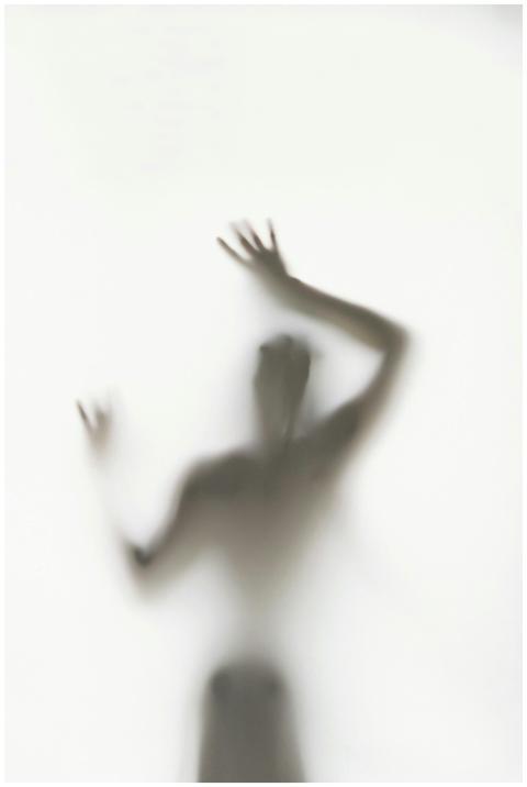 Blurry silhouette of a person with hands raised be