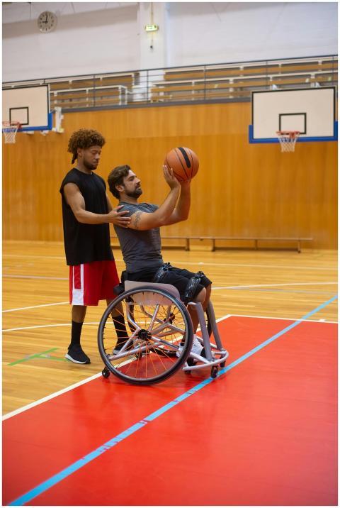 A personal trainer assists a wheelchair-bound athl